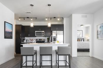 A modern kitchen with a bar area and a painting on the wall.